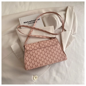 Detail of light pink crossbody bag with M-letter print on a white blazer