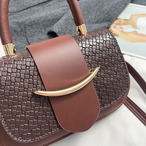 Detail of woven texture and smooth leather on handbag with gold metal accents