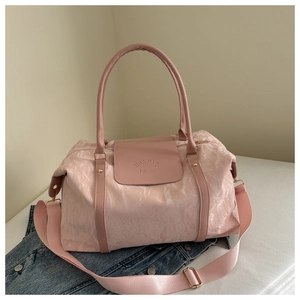 Détail du sac de voyage rose montrant la texture matelassée et le logo HuaJiao