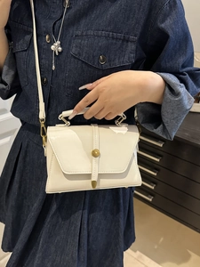 Elegant white patent leather crossbody handbag with gold buckle and adjustable strap
