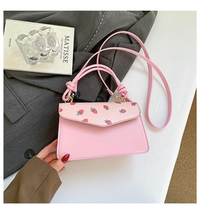 Detail of pink handbag with strawberry print cover and a unique knotted top handle design