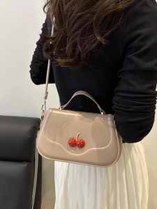 Beige faux leather crescent bag with rhinestone cherry charm on model for minimalist style