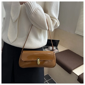 Détail d'un sac sous le bras en cuir marron brillant avec boucle en métal doré chic