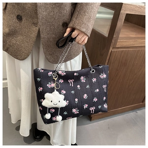 Close-up of black floral tote bag with chain strap and plush cloud charm detail