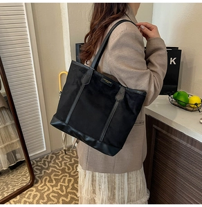 Black large capacity tote bag shown on shoulder with minimalist fashion design