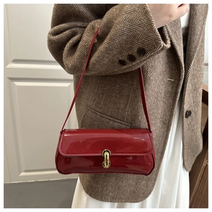 Détail du sac sous l'aisselle en cuir verni bordeaux avec fermoir doré vintage capsules