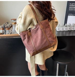 Detail showing retro brick-red tote bag with dark brown leather trim and golden nameplate