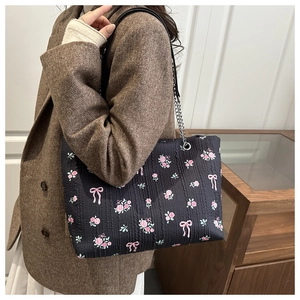 Detail of floral tote bag showing textured fabric with rose pattern and chain strap