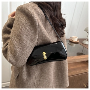 Détail d'un sac à bandoulière en cuir verni noir avec boucle en métal doré en forme de U