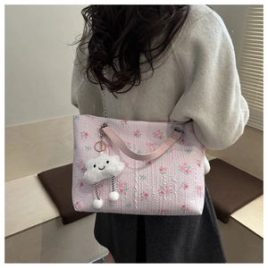Detail of pink floral corduroy tote bag with plush cloud charm and metal chain strap