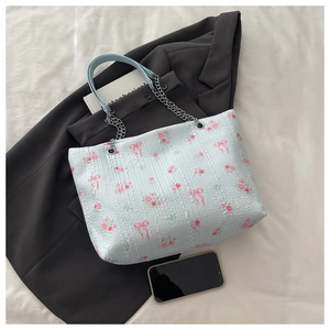 Detail of light blue floral tote bag with silver chain strap and ruffled texture