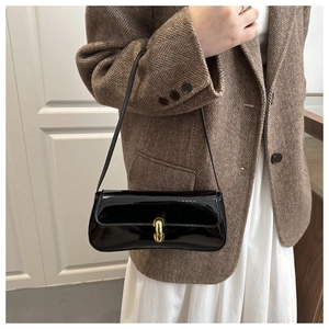 Détail d'un sac à bandoulière en cuir verni noir avec un fermoir métallique doré élégant