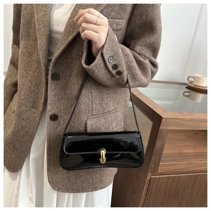 Détail du sac porté épaule en cuir verni noir avec fermoir doré et bandoulière élégante