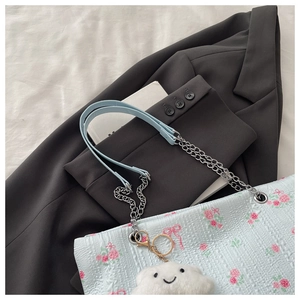 Detail of light blue floral tote bag with chain strap and plush cloud charm