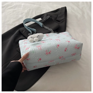 Detail of light blue floral jacquard texture bag with chain strap and lamb charm
