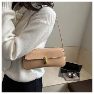 Détail d'un sac à bandoulière en cuir verni abricot avec fermoir doré sur modèle