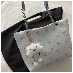 Close-up of pleated floral tote bag with silver chain and white cloud plush charm