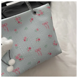 Detail of light blue seersucker tote bag with rose print and silver chain strap