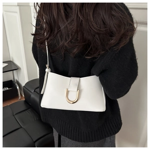 Vue détaillée du sac en cuir blanc avec une boucle en métal doré en forme de U élégante