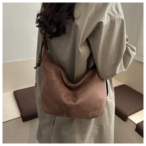 Brown suede hobo tote bag shown in a side-view lifestyle shot with a khaki trench coat