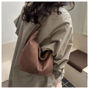 Close-up of brown faux suede dumpling bag with adjustable strap and textured finish
