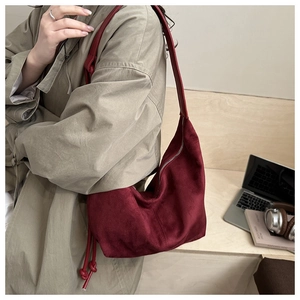 Detail of burgundy suede hobo bag featuring side knot design and zipper closure