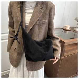 Detail of minimalist black crescent bag with knotted strap and soft matte texture