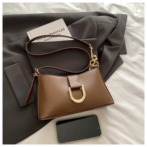 Détail du sac à bandoulière marron en similicuir avec boucle en U dorée et chaîne en métal