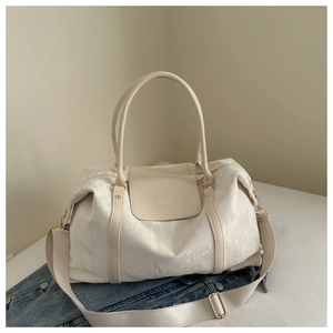Détail du sac de voyage blanc cassé avec texture froissée et logo de la marque