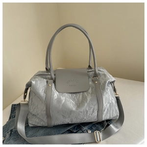 Détail du sac gris brillant à texture froissée avec logo embossé et bandoulière large