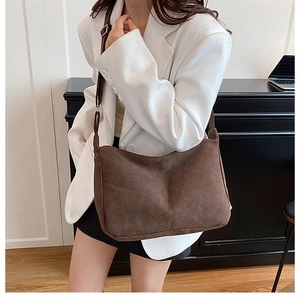Vue détaillée du sac bandoulière en daim marron avec coutures verticales et sangle