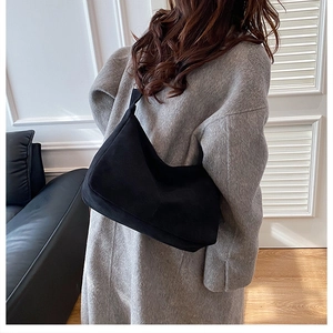 Close-up of black matte suede shoulder bag featuring a soft crescent shape and large capacity