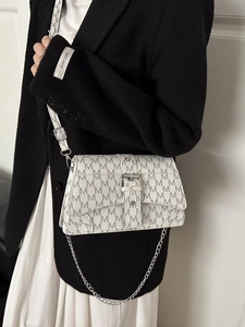 White crossbody bag with grey M logo print and silver chain strap shown on model