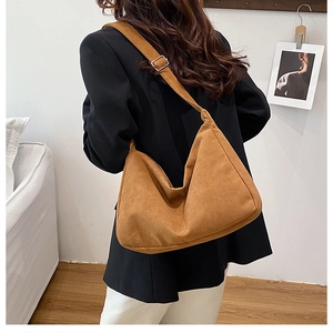 Brown suede-texture crescent shoulder bag styled on model in a modern interior