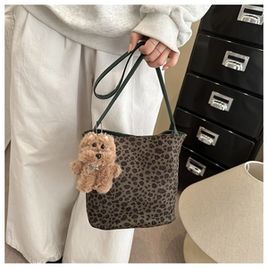 Detail of leopard print bucket bag with green leather strap and plush dog charm