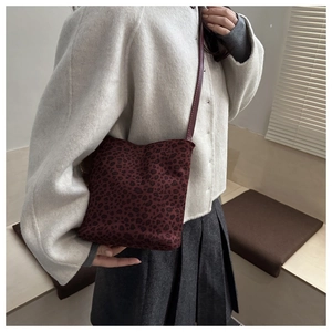 Detail of dark red leopard print bucket bag with slim leather strap on a model
