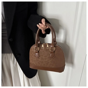 Detail of vintage leopard print shell bag with brown leather handles and gold zippers
