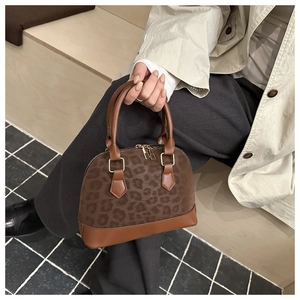 Detail of leopard print shell bag with brown leather trim and golden zippers