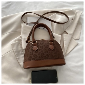 Detail of vintage brown leopard shell bag with gold zippers on a beige blazer background