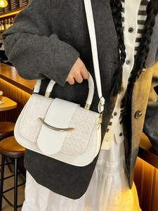 Elegant white woven leather handbag with gold buckle shown on a stylish model