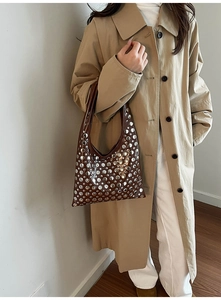 Detail of a brown bucket bag featuring stylish silver metal studs and polished faux leather