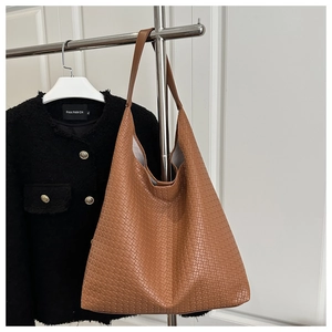Détail d'un sac cabas marron à texture tressée avec silhouette triangulaire élégante