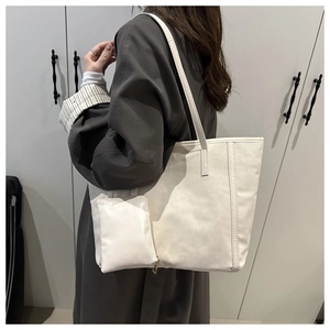 Minimalist white tote bag with matching pouch shown on shoulder in a lifestyle setting