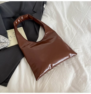 Vue de dessus d'un sac hobo en cuir marron foncé brillant sur un tissu blanc