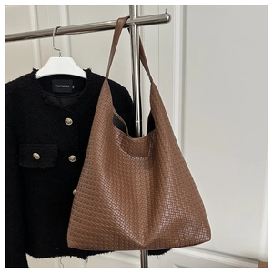 Détail de la texture en cuir tressé marron sur un sac cabas minimaliste avec bandoulière