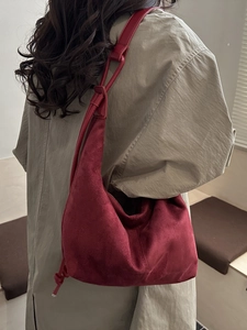 Minimalist burgundy suede tote bag with decorative knot handle shown on shoulder