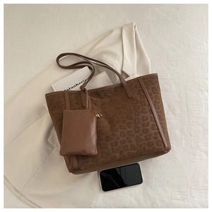 Detail shot of leopard print tote bag with matching pouch on beige blazer and book