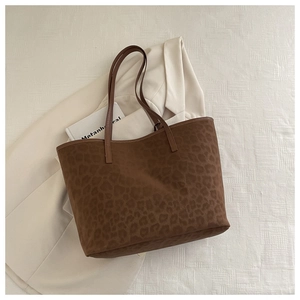 Detailed top view of a leopard print tote bag placed on a neutral beige blazer fabric