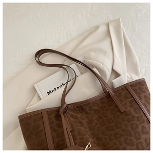 Macro detail of leopard print tote bag featuring brown leather straps and gold metal zipper