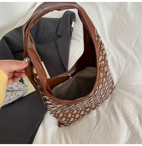 Détail d'un sac seau en cuir marron avec rivets argentés et fermoir magnétique